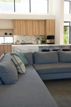 Large grey sectional sofa is anchoring living room with teal pillow, marble Stock Photos