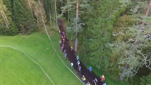 Large group of cyclists riding onto a narrow forest track during a bike race Stock Footage 88489591