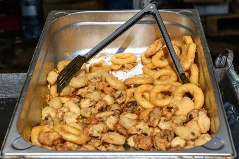 Large group of freshly deep fried calamari rings and mussels on display for sale Stock Photos