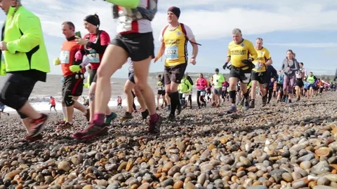 Large group of people running on the pebble beach Stock Footage 125963555