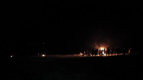 Large group of people surrounding a big hot pyre during a pitch black night. Stock Footage 132962592