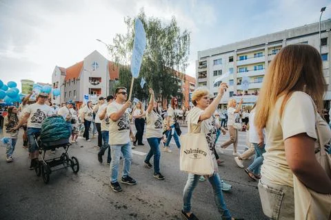 A large group of people walking through a city neighborhood. Stock Photos