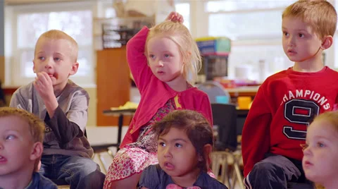 A large group of preschool students sit together and listen for show and tell Stock Footage 34004990