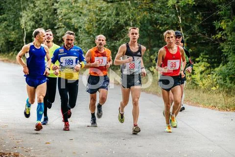 Large group of runners men middle-aged and young run through Park Stock Photos