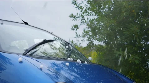 A large hail during a storm causes damage to a parked car Stock Footage 220083196