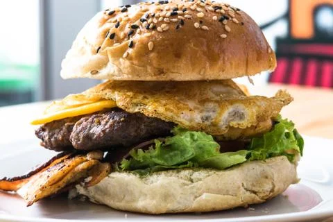 Large hamburger containing egg, banana, cheese and meat on a white plate Stock Photos