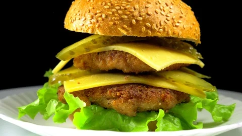 A large hamburger with meat and cheese rotates on a plate Stock Footage 88362001