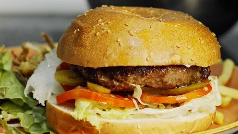Large hamburger placed on a bun with vegetables in slow motion Stock Footage 94458388
