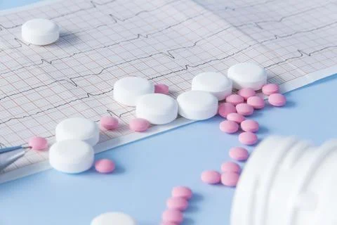 A large handful of pink and white medicines are spilled from a jar on a heart Stock Photos