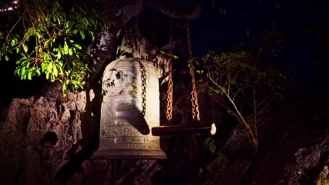 Large Hanging Bronze Bell on Rock Wall at Night Stock Footage 344018533