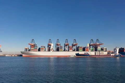 Large harbor cranes loading container ships in the port of Rotterdam Stock Photos