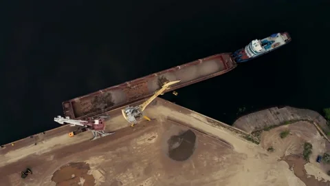 Large harbor cranes onshore at the quay unload a river gravel barge onto a large Stock Footage 154675030