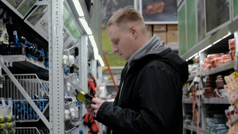 Large hardware store. Young man in a hardware store. A man in a hardware store Stock Footage 250466947