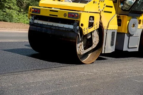 Large heavy skate ramming a new asphalt in the lane of the road. Close-up Stock Photos