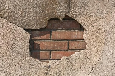 A large hole of plaster through which the brickwork is visible. Old destroyed 스톡 사진