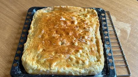 A large homemade pie of a rectangular shape with a shiny golden crust cools on a Stock Photos