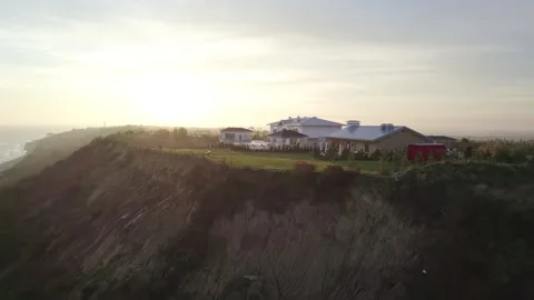 A large house on the edge of a cliff by the ocean at dawn Stock Footage 265242084