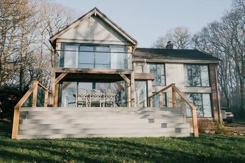 A large house with a large deck and a staircase leading up to the front door Stock Photos