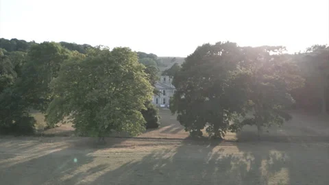 A large house sits in a field with trees in the background Stock Footage 301628191