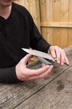 Large hunting knife being sharpened Stock Photos
