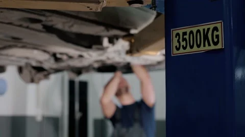 Large hydraulic jack. auto mechanic repairs the gearbox in a modern car Stock Footage 239471512