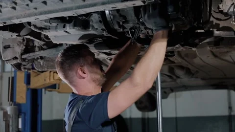 Large hydraulic jack. auto mechanic repairs the gearbox in a modern car.  Stock Footage 239471778