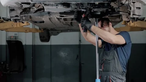 Large hydraulic jack. auto mechanic repairs the gearbox in a modern car. Stock Footage 239471784