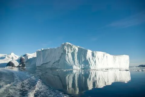 Large iceberg and its reflection in the southern ocean on a summer. Stock Photos