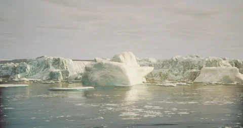 Large icebergs float in a calm ocean under a cloudy sky in an Arctic landscape Vídeos de archivo 304526729