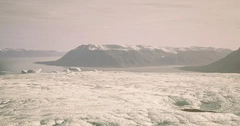 Large icebergs float on a serene glacial lake surrounded by mountains Stock Illustration