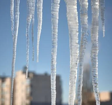 Large icicles over defocused winter urban cityscape background Stock Photos