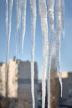 Large icicles over defocused winter urban cityscape background Stock Photos