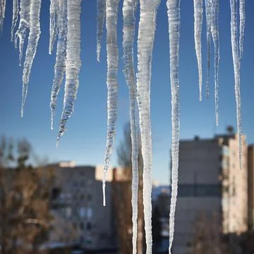 Large icicles over defocused winter urban cityscape background Stock Photos