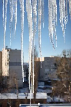 Large icicles over defocused winter urban cityscape background Stock Photos