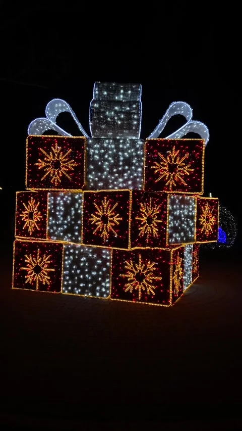 Large, illuminated gift box display with red boxes adorned with golden stars and Stock Footage 293092321