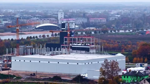 Large industrial building under construction with cranes and autumn city Video stock 325057378