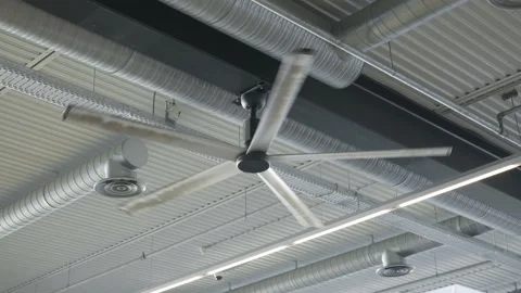 Large industrial ceiling fan rotates under modern building roof structure. Stock Footage 343983449