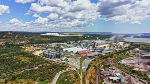 Large industrial complex sits near a river with green hills and clouds in the Stock Footage 341100185