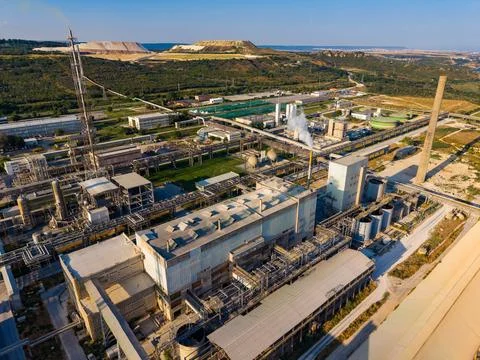 A large industrial complex stands next to mining land. Pipes and structures a Stock Photos