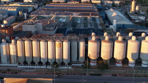 Large industrial facility with rows of metal storage silos bathed in golden 動画素材 345103469