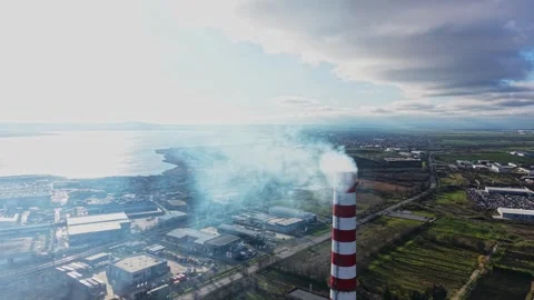 Large industrial smoke stack releases smoke over water and land Stock Footage 332207875
