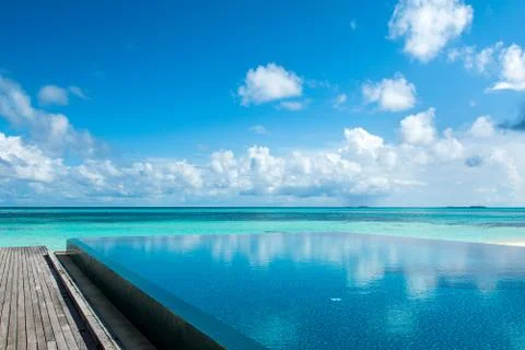Large infinity pool on the shores of the Indian Ocean with sunbeds and umbrel Stock Photos
