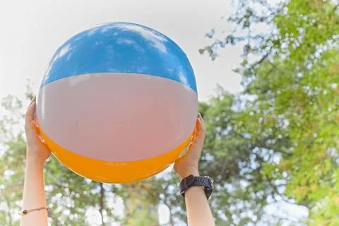 A large inflatable multi-colored children's ball in the hands of a child Stock Photos