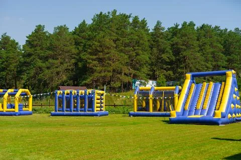 Large inflatable obstacles and slides are set up on green lawn. Stock Photos