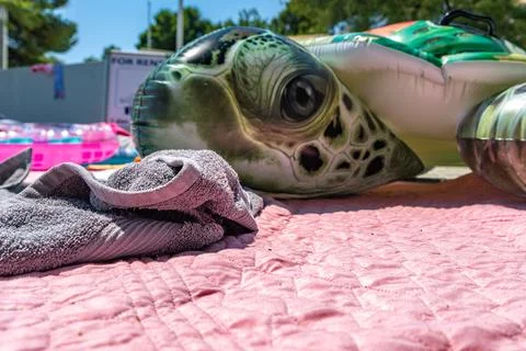 Large Inflatable Turtle on Pink Beach Blanket by the Sea During Summer Vacati Stock Photos