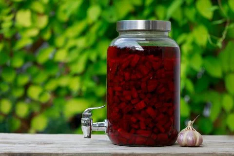 Large jar full of red beetroot with cap and tap. Green background. Foto stock
