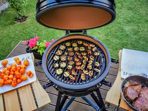 Large kamado type barbeque grill with beef steaks and vegetables ready to cook Stock-Fotos