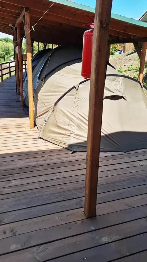Large Khaki Camping Tent Standing on Wooden Platform Under Shelter Stock Footage 339085554