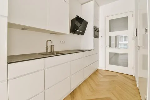 A large kitchen with white cabinets and a sink Stock Photos