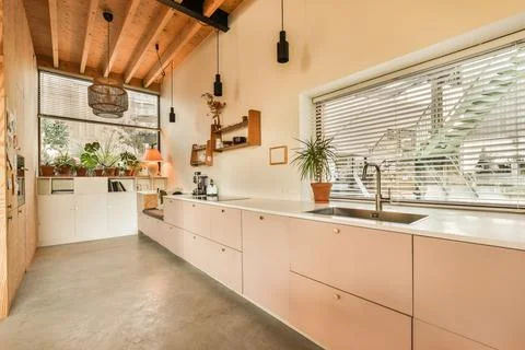 A large kitchen with white cabinets and a large window Stock Photos